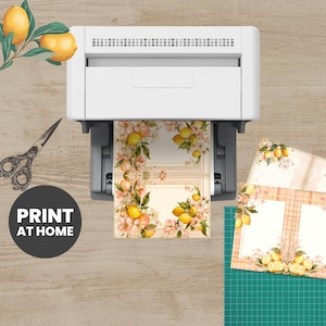 a printer, scissors, and some printed materials on a wooden surface.