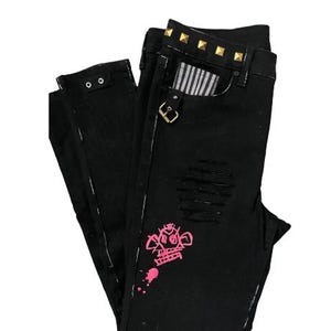 Puede incluir: Vaqueros negros con detalles desgastados, con un gr&aacute;fico rosa y tachuelas doradas en la cintura. Los vaqueros tienen un forro de bolsillo a rayas y un cierre de hebilla.