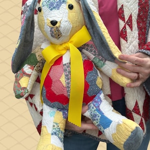 May include: A handmade patchwork bunny doll with a yellow ribbon around its neck. The bunny features a variety of colorful fabric patterns, including floral and geometric designs. The doll has long, floppy ears and black button eyes.