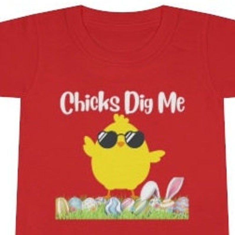 May include: Red t-shirt with a yellow chick wearing sunglasses and the text "Chicks Dig Me". The chick is standing on a bed of green grass with colorful Easter eggs.