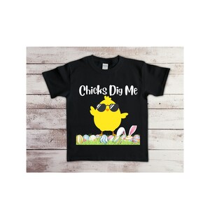 May include: Black t-shirt with a yellow chick wearing sunglasses and the text "Chicks Dig Me". The chick is standing on a bed of green grass with colorful Easter eggs.