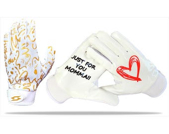 May include: White football gloves with gold graffiti-style designs on one glove and the text "JUST FOR YOU MOMMA!!" and a red heart on the other. The gloves are designed for athletic use.