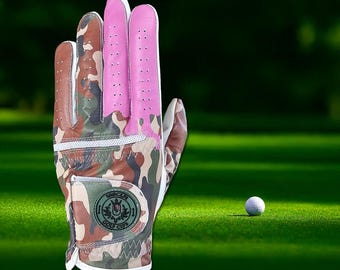 May include: A camouflage golf glove with a pink palm and a white logo that says "Soccer Golf Club".