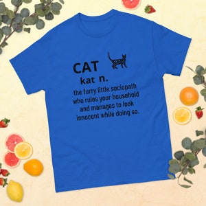 May include: A blue t-shirt with a black cat illustration and the text "CAT kat n. the furry little sociopath who rules your household and manages to look innocent while doing so."