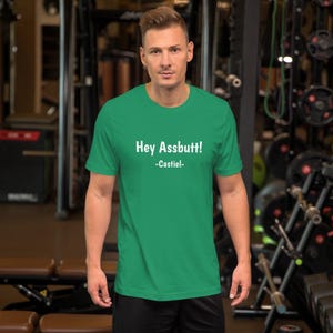 Könnte beinhalten: Ein grünes T-Shirt mit dem Aufdruck "Hey Assbutt! -Castiel- " in weiß.