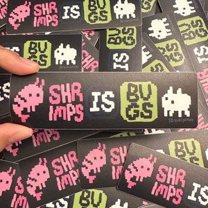May include: Black rectangular sticker with pixelated pink shrimp and the words "SHR IMPS IS BUGS" in white and green. A pixelated white creature is also present. The sticker is held by a hand, with other similar stickers in the background.