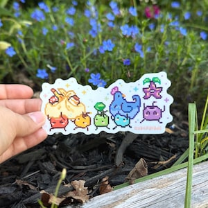 May include: A die-cut vinyl sticker featuring pixel art characters including a large beige dumpling, a blue bird, a purple star-shaped creature, and several small colorful round figures. The sticker includes the text quailparade in small letters.