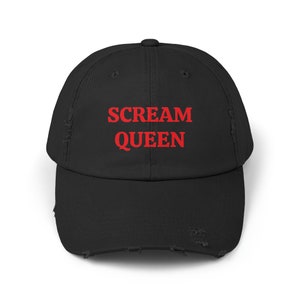 May include: Black distressed baseball cap with the words "SCREAM QUEEN" in red block letters across the front. The cap has a curved brim and a distressed, worn look.