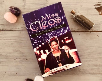 May include: Purple tarot card deck box with the text "Miss Cleo's Tarot Power Deck" and a photo of a woman holding a tarot card.