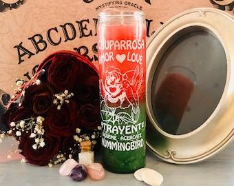 May include: A red, white, and green candle with the words "Chuparrosa Amor Love" and "Trayente Acuerdate Hummingbird" printed on it. The candle is sitting on a wooden surface with a small bottle of crystals, two pink and purple crystals, and two white stones.