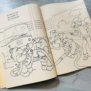 Peut inclure: Un livre ouvert avec une illustration en noir et blanc d'oursons c&acirc;lins dans une caserne de pompiers. Le camion de pompiers porte le num&eacute;ro 21. Le texte dit : "C'est amusant de voir l'int&eacute;rieur de la caserne."