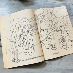 Peut inclure: Livre ouvert avec des illustrations en noir et blanc. Une page montre un gar&ccedil;on et un ours dans une pizzeria. L'autre page montre un gar&ccedil;on et des ours &agrave; une fontaine. Le texte dit : "Fire fighting makes you hungry" et "and thirsty."