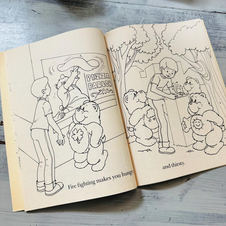 Peut inclure: Livre ouvert avec des illustrations en noir et blanc. Une page montre un gar&ccedil;on et un ours dans une pizzeria. L'autre page montre un gar&ccedil;on et des ours &agrave; une fontaine. Le texte dit : "Fire fighting makes you hungry" et "and thirsty."