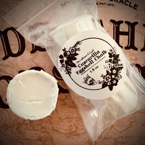 May include: A white plastic bag containing three white sticks of cascarilla eggshell chalk. The bag has a white label with black text that reads "Occulture Crypt Cascarilla Eggshell Chalk 1.5 oz".