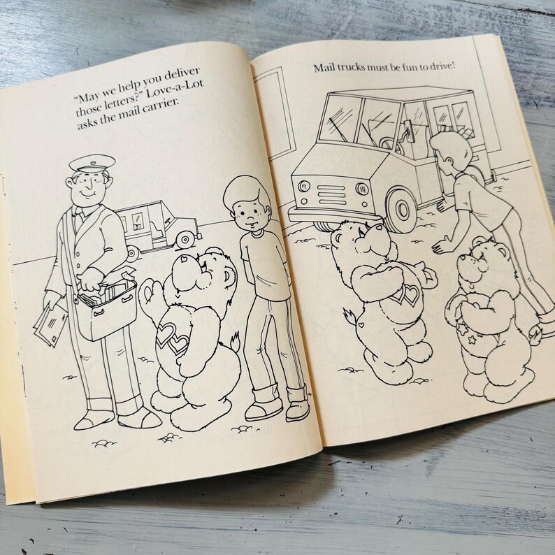Peut inclure: Illustration d'un livre ouvert avec un facteur, des enfants et des Bisounours. Le texte dit : &laquo; Pouvons-nous vous aider &agrave; livrer ces lettres ? &raquo; et &laquo; Les camions de courrier doivent &ecirc;tre amusants &agrave; conduire ! &raquo; Les Bisounours ont des motifs de c&oelig;ur et d'&eacute;toile.