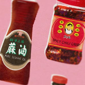 May include: Close-up of two bottles of Asian condiments against a pink background. One bottle is labeled "PURE SESAME OIL" with Chinese characters. The other is "SPICY CHILI CRISP" with a cartoon image and Chinese characters.