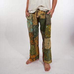 Peut inclure: Pantalon en patchwork aux tons terreux, notamment vert olive, jaune moutarde et marron. Le tissu présente un motif répétitif de champignons et d'éléments botaniques. Ce pantalon est doté d'une taille à cordon de serrage et de poches latérales.