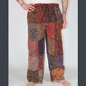 以下が含まれることがあります： 茶色、赤、紫、緑の色合いのマルチカラーパッチワークパンツ。 パンツは、ドローストリングウエストとパッチワークデザインが特徴です。 スカルと稲妻のグラフィックが右脚の下部にあります。 パンツは柔らかく快適な素材で作られています。
