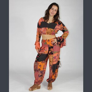 May include: A patchwork print pantsuit with a cropped top and long sleeves. The top and pants are both a mix of orange, pink, black, and white.