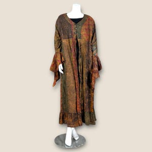 May include: A long, brown, and orange patterned duster with a ruffled hem and bell sleeves. The duster is open in the front and has a button closure.