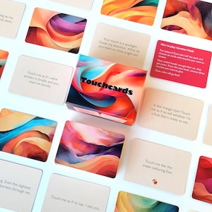 May include: A collection of Touchcards with abstract art designs in shades of orange, pink, and blue. The box of cards is centered, with individual cards scattered around. Each card has a unique phrase.