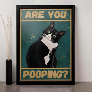 Puede incluir: Un p&oacute;ster de estilo vintage con un gato blanco y negro mirando hacia arriba y el texto "Are you pooping?" en letras amarillas sobre un fondo verde.