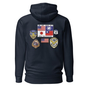 Puede incluir: Sudadera con capucha azul marino con múltiples parches y banderas. La parte posterior de la sudadera muestra el texto "FAR EAST CRUISE 63-4" encima de un diseño rectangular con las banderas de Estados Unidos, Japón y Taiwán. También es visible el texto "USS GALVESTON".