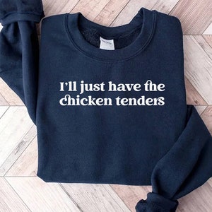 以下が含まれることがあります： 白い文字で「I'll just have the chicken tenders」とプリントされた紺色のスウェットシャツです。