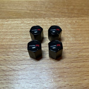 Peut inclure: Quatre capuchons de valve noirs avec un logo "TYPE R" rouge.