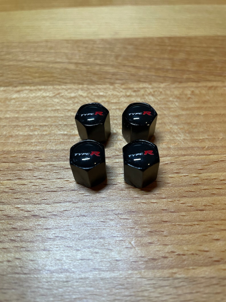 Peut inclure: Quatre capuchons de valve noirs avec un logo "TYPE R" rouge.