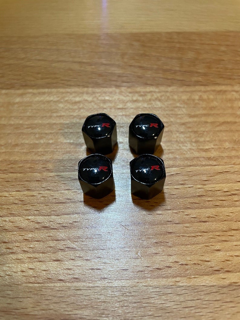 Peut inclure: Quatre capuchons de valve de pneu noirs avec un logo "TYPE R" rouge.