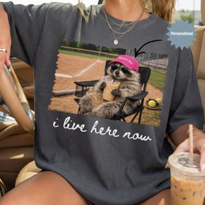 Personalized I Live Here Now Raccoon Softball Mom Shirt, Custom Funny Raccoon Softball Mom T-Shirt