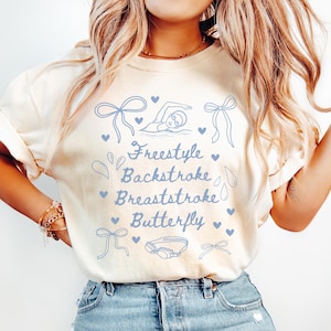 May include: A white t-shirt with a blue design of a swimmer and the words "Freestyle", "Backstroke", "Breaststroke", and "Butterfly".