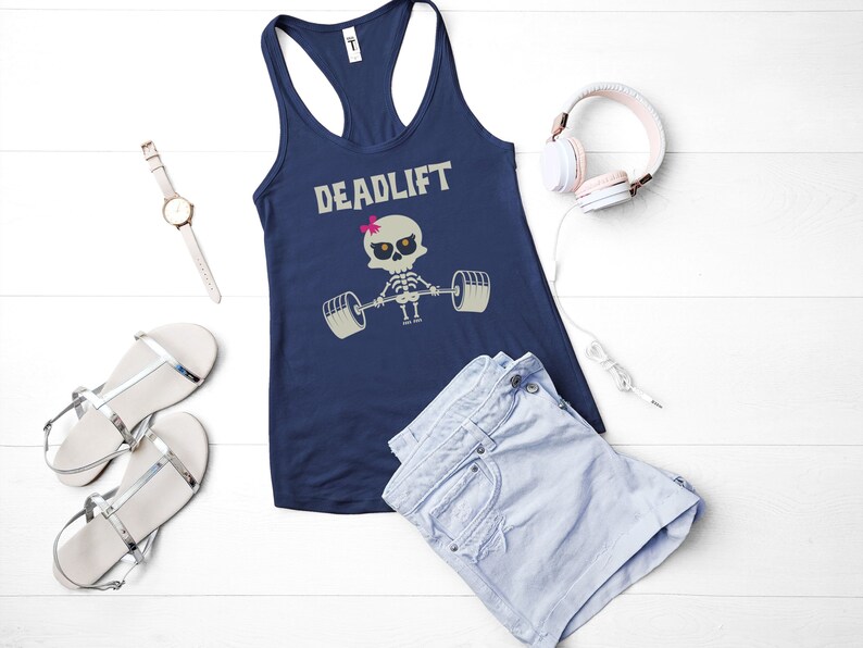 May include: Navy blue racerback tank top with the word "DEADLIFT" above a cartoon skeleton lifting weights. The skeleton has a pink bow. The image also includes a watch, sandals, shorts, and headphones.