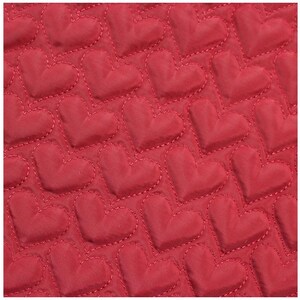 May include: Close-up of a red fabric with a quilted heart pattern. The hearts are evenly spaced and stitched with a contrasting thread. The fabric has a smooth texture and a slight sheen.