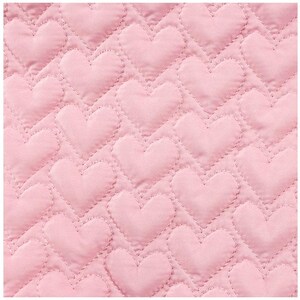 May include: Close-up of a pink quilted fabric with a repeating heart pattern. The hearts are evenly spaced and stitched onto the fabric, creating a textured surface. The color is a soft, pastel pink.