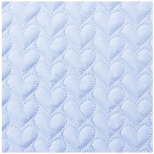 May include: A light blue quilted fabric with a repeating heart pattern. The hearts are stitched onto the fabric, creating a textured surface. The overall design is soft and romantic, suitable for bedding or decorative items.