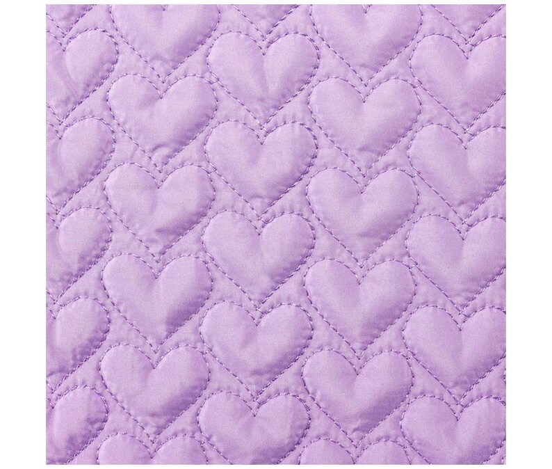 May include: Close-up of a lavender quilted fabric with a repeating heart pattern. The hearts are stitched with a contrasting thread, creating a textured effect. The fabric has a soft, padded appearance, suggesting a cozy textile.