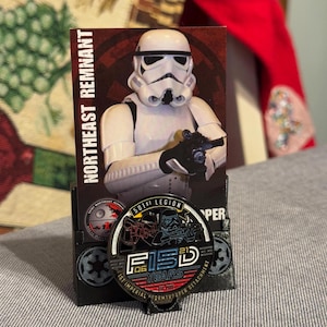 以下が含まれることがあります： スターウォーズのコレクターズアイテム。ストームトルーパーのフィギュアが特徴です。「Northeast Remnant」と書かれたカードには、「501st Legion」と「FISD 06 Years」の文字が入ったコインが表示されています。コインは黒、シルバー、赤です。