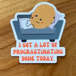 May include: A sticker featuring a cartoon potato character relaxing on a small gray couch with a pillow. The potato has a smiling face. The text "I GOT A LOT OF PROCRASTINATING DONE TODAY" is below the couch in orange letters.
