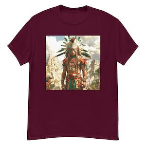 Peut inclure: Un t-shirt marron avec une image colorée d'un homme amérindien portant une coiffe à plumes et debout devant des ruines anciennes.