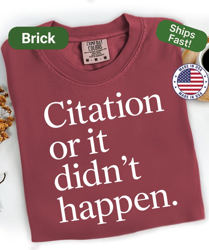 May include: Brick-colored t-shirt with the text "Citation or it didn't happen" in white. The shirt has a crew neck and short sleeves. The tag reads "Comfort Colors". The shirt is made in the USA.
