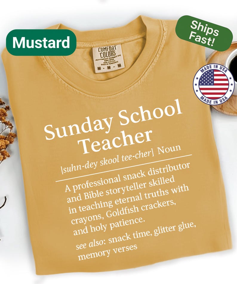K&ouml;nnte beinhalten: Senffarbenes T-Shirt mit dem wei&szlig;en Text "Sunday School Teacher". Das Shirt enth&auml;lt eine Definition und eine Liste von Lehrerqualit&auml;ten. Ein gr&uuml;nes Etikett lautet "Mustard" und ein anderes "Ships Fast!"