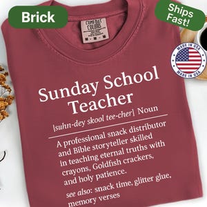 K&ouml;nnte beinhalten: Ziegelrotes T-Shirt mit wei&szlig;em Text "Sunday School Teacher". Die Definition beinhaltet "professioneller Snack-Verteiler" und "Bibel-Erz&auml;hler". Mit "Made in USA" Emblem und "Ships Fast!" Aufkleber.