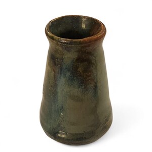 May include: A handmade ceramic vase with a dark green and brown glaze. The vase has a flared shape, wider at the base and narrowing towards the top. The rim is a darker brown color.