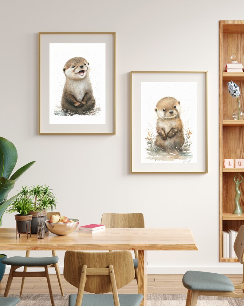 Op de afbeelding: Twee ingelijste aquarellen van otters. De otter in het linker schilderij zit rechtop en glimlacht. De otter in het rechter schilderij staat rechtop en kijkt naar de kijker. Beide otters zijn bruin en wit.