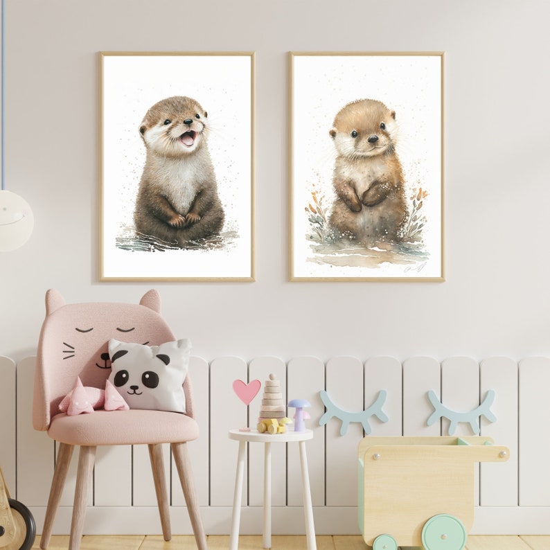 Op de afbeelding: Twee ingelijste aquarellen van otterwelpen. De otter links zit met gekruiste pootjes. De otter rechts staat met gekruiste pootjes. Beide otters hebben een lichtbruine vacht en kijken naar de camera.