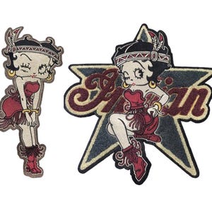 May include: A white ceramic mug with a black handle and the text "But First, Coffee" in a black, handwritten-style font. The mug is on a white surface.