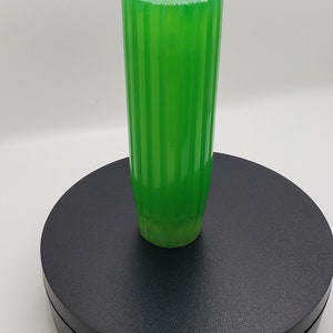 May include: A vibrant, translucent green cylindrical handle featuring a vertical ribbed texture along its length. The object has a flat, circular top surface and a slightly tapered base, showcasing a smooth, glossy finish throughout its structure.