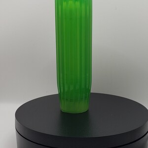 May include: A translucent, vibrant green cylindrical vase featuring a vertical ribbed texture along its entire length. The vase has a straight, uniform profile with a flat top opening and a slightly tapered base, showcasing a bright, semi-transparent finish.